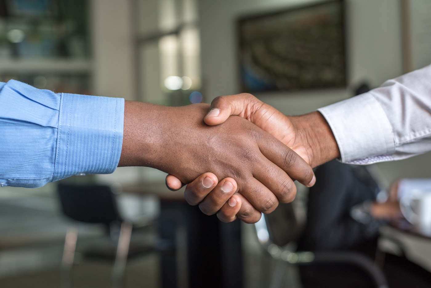 A handshake marking the merger of four firms into ARTISAN